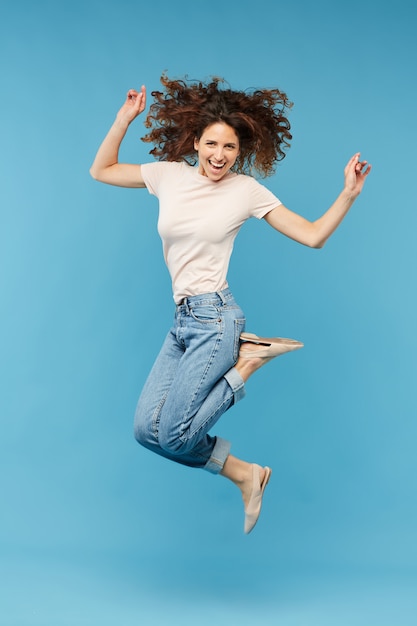 Young joyful brunette woman leaping in isolation