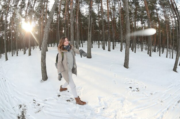 A young and joyful Caucasian girl in a brown coat is throwing 