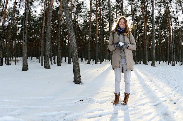 A young and joyful Caucasian girl in a brown coat in the snow