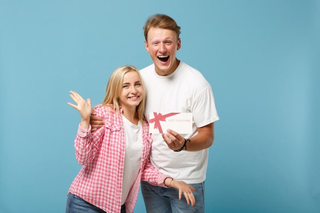 Young joyful couple two friends guy and woman in white pink empty t-shirts posing 