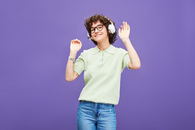 Young joyful woman in headphones listening to music and dancing