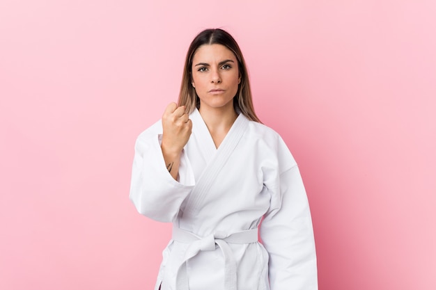 Young karate woman showing fist, aggressive facial expression.