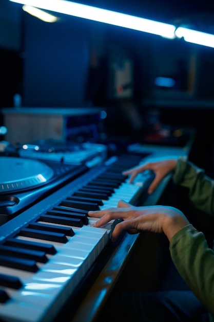 Young keyboardist musician artist playing on synthesizer in neon light recording studio