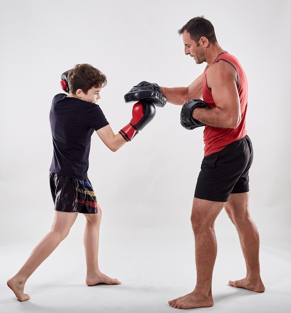 Young kickbox fighter hitting mitts with his coach