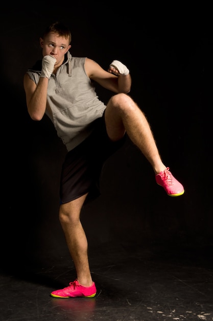 Young kickboxer ready to throw a punch while balancing on one leg