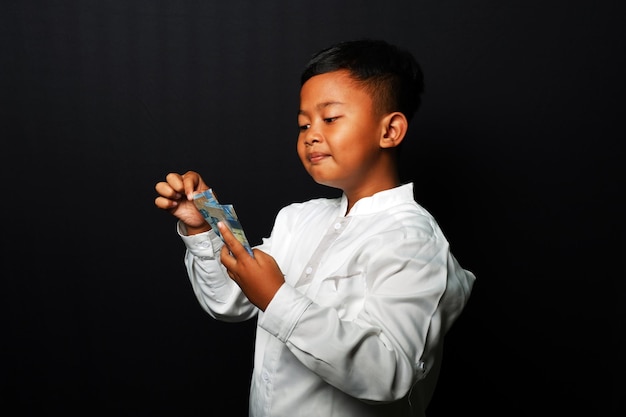 Young kid holding a lot of money isolated on black background