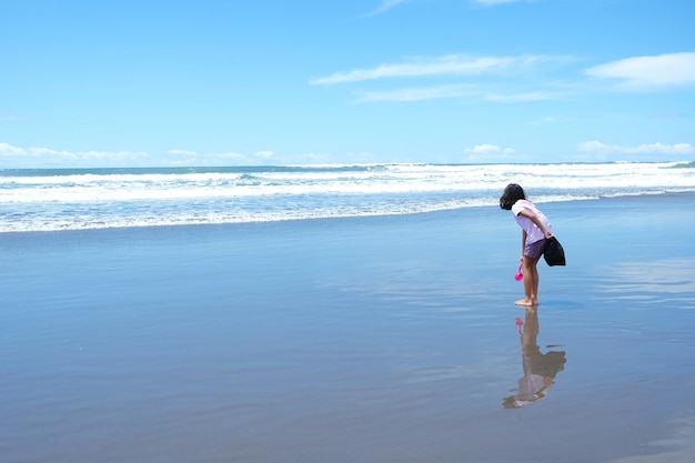 Photo young kid playing alone in the beach during summer