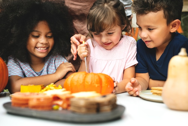 Young kids carving Halloween jack-o&#39;-lanterns