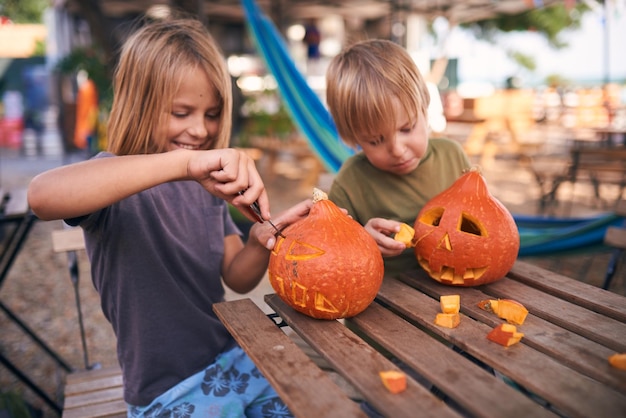 Young kids carving Halloween pumpkin