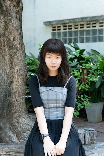 Foto giovane donna coreana in una donna casuale dell'adolescente dei bei capelli lunghi che esamina macchina fotografica in giardino.