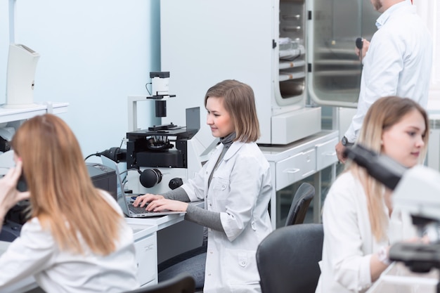 Giovani assistenti di laboratorio che utilizzano computer portatile per l'esperimento di laboratorio chimico