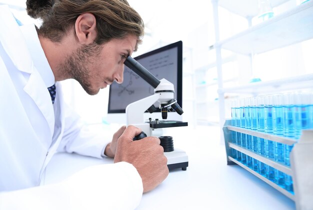 Young laboratory scientist looking at microscope in laboratory