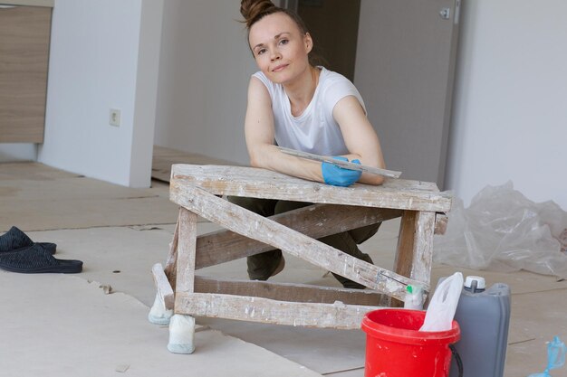 Photo young lady between 30 and 40 years old is renovating apartment.