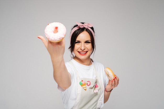 Young lady confectioner holding fresh tasty donut in hands