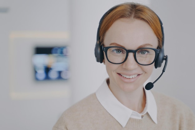 Foto giovane signora consulente del call center ragazza amichevole europea in cuffia che parla con il cliente in agenzia