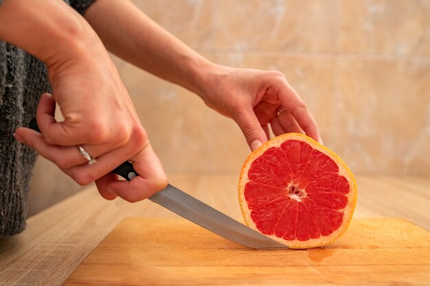 The young lady cuts a slice of grapefruit