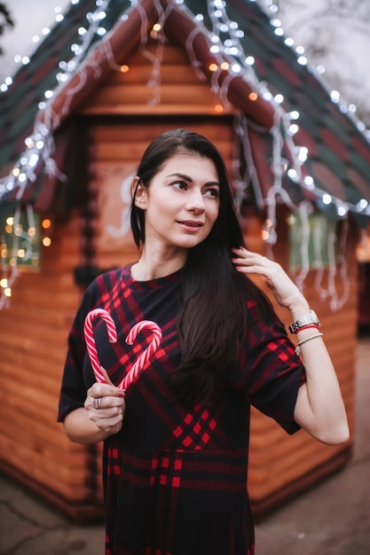 young lady in dress standing near decorated house for Christmas