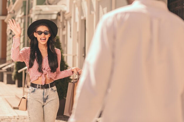 Young lady feeling excited and waving to friend in the street