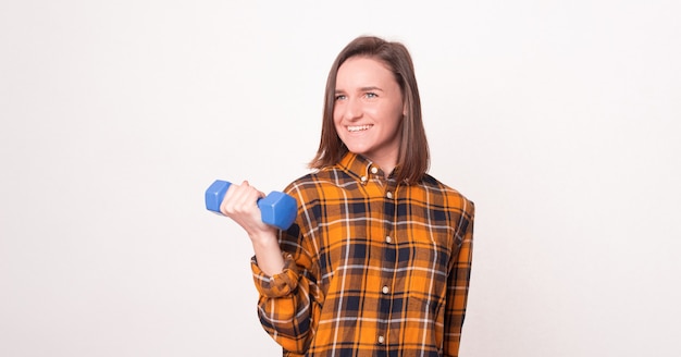 Young lady holding a blue dumbbell over white background.