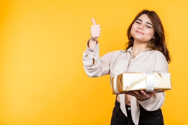 Young lady holding her present and gesture thumb up High quality photo