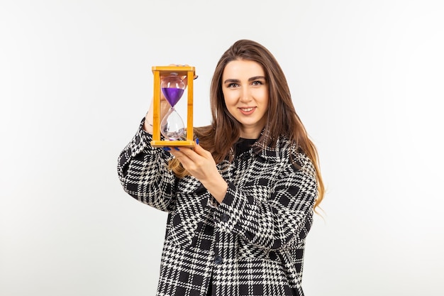 A young lady holding hourglass and looking at the camera