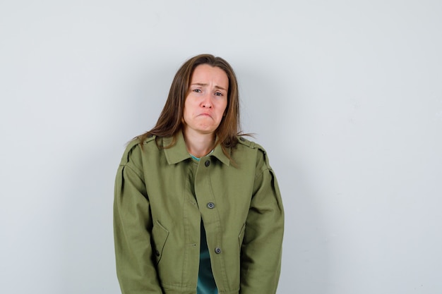 Young lady looking at camera in t-shirt, jacket and looking offended. front view.