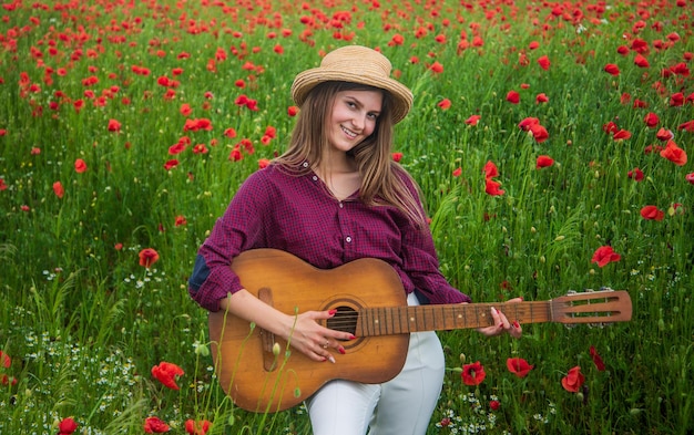 Young lady in poppy field with guitar music