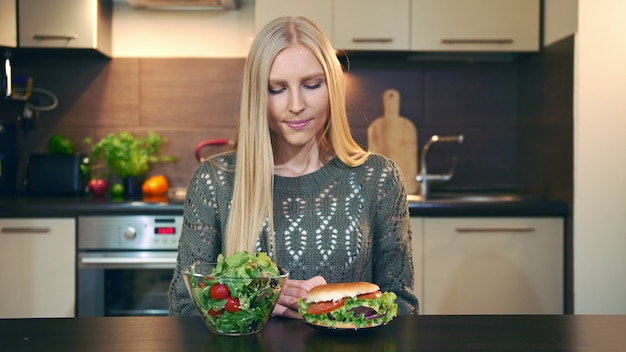 Young lady preferring salad to hamburger