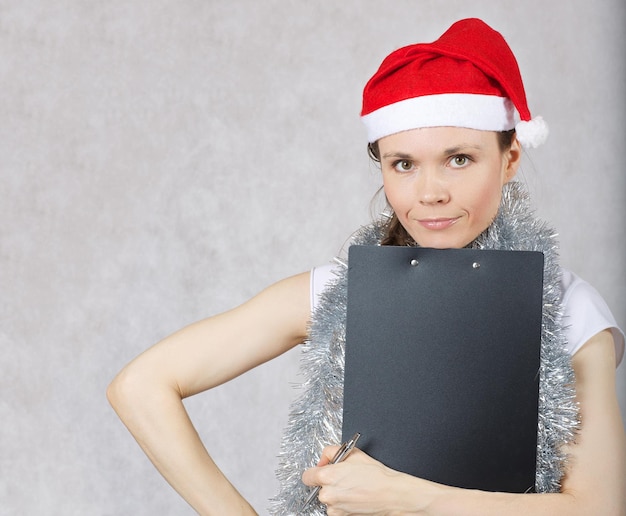 Foto giovane signora con un cappello da babbo natale, spazio libero per un messaggio.