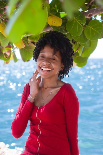 Photo young lady smiling sitting on rocks near the sea