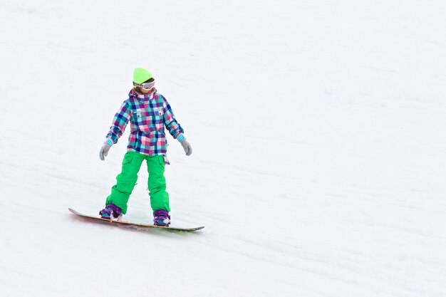 Snowboarder della giovane signora che scivola giù la collina