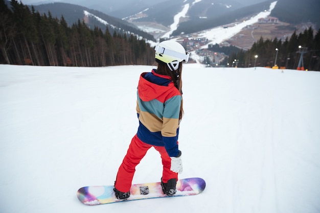 凍るような冬の日の斜面で若い女性のスノーボーダー