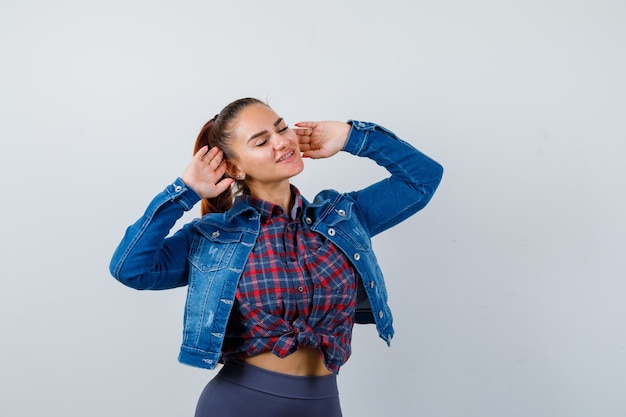 Young lady stretching upper body in shirt, jacket and looking relaxed. front view.