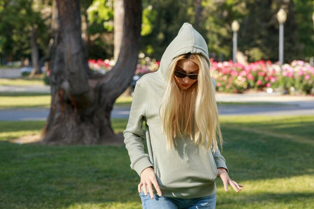 Young lady wearing casual clothes and put her hands into her pocket at the park