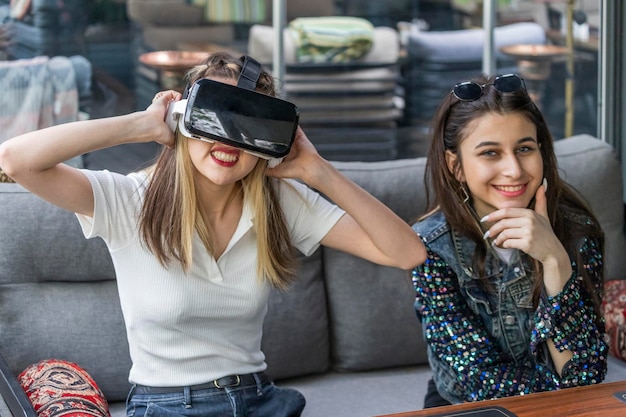 Young lady wearing VR set and her friend smiling to the camera