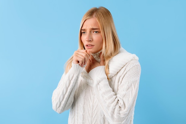 Young lady with throat pain coughing blue background