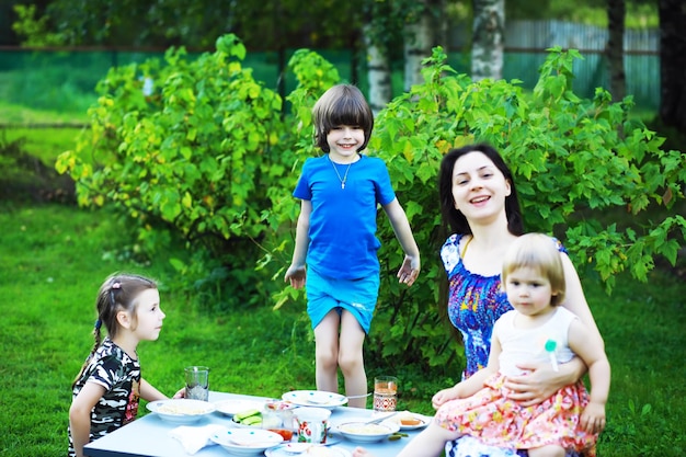 여름 아침 소풍에서 젊은 대가족 아이들과 함께 아름다운 어머니가 공원에서 아침을 먹고 있다