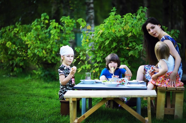 A young large family at a picnic on a summer morningMother with children is having breakfast in the park