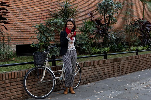 Young Latin American businesswoman standing next to her vintage bicycle sending a voicemail message