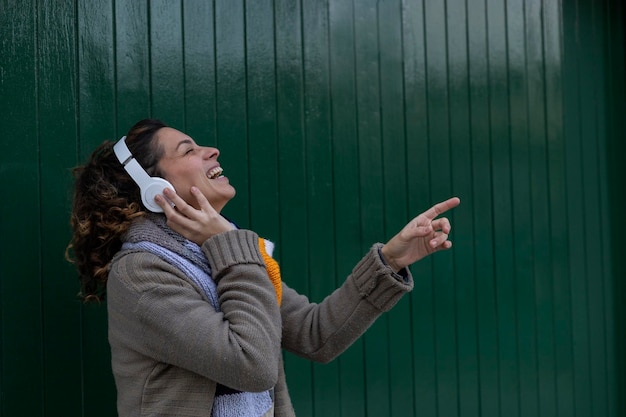 Photo a young latin american girl listens to music with her headphones laughs sings and has a good time