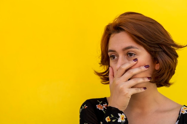 Young Latin American woman 23 makes a gesture of shock while with her right hand she covers her mouth Valentine's Day concepts gestures and expressions