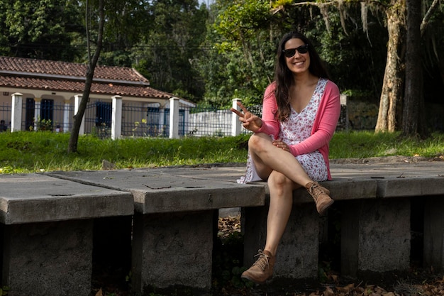 33세의 젊은 라틴 아메리카 여성은 봄이 온 것에 대해 행복해하며 그녀는 태양의 따스함을 받는 공원에 앉아 있습니다.