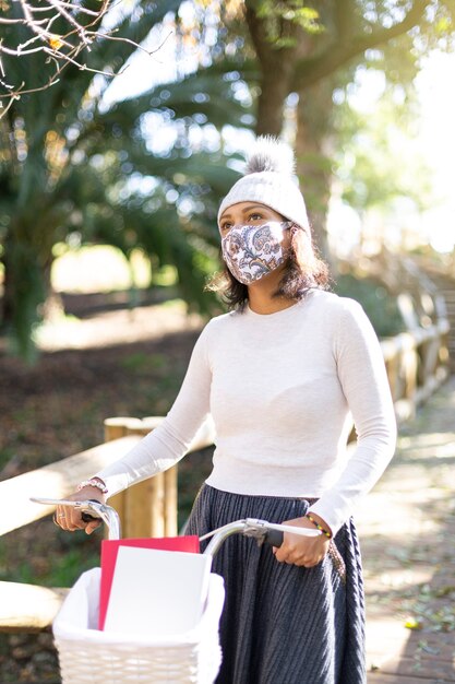 Young latin american woman walking with her bicycle