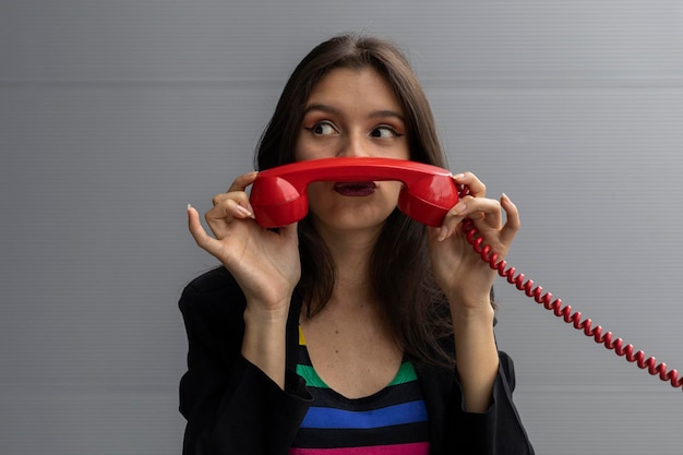 Young Latin American woman with a red headset and positive attitude poses with funny gestures Youth and vintage technology concept