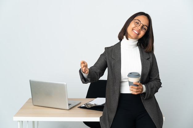 Молодая латинская деловая женщина, работающая в офисе, изолированном на белом, представляет и приглашает прийти с рукой