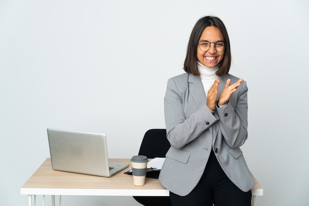 Young latin business woman working in a office isolated on white wall applauding after presentation in a conference