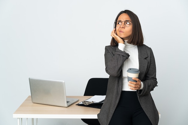 Young latin business woman working in a office isolated on white wall frustrated and covering ears