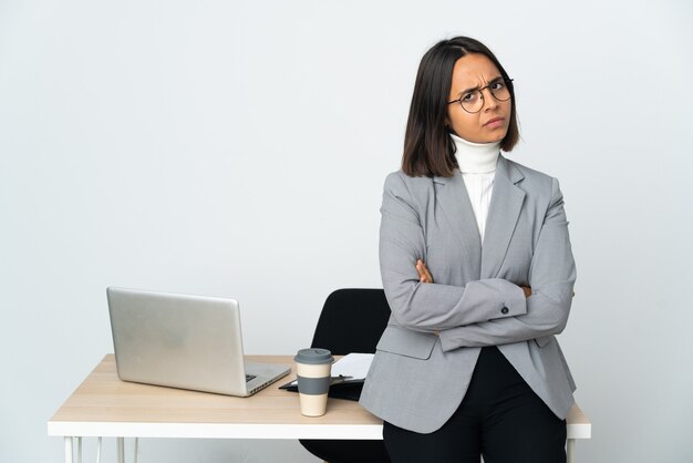 Giovane donna d'affari latino che lavora in un ufficio isolato su bianco con espressione infelice