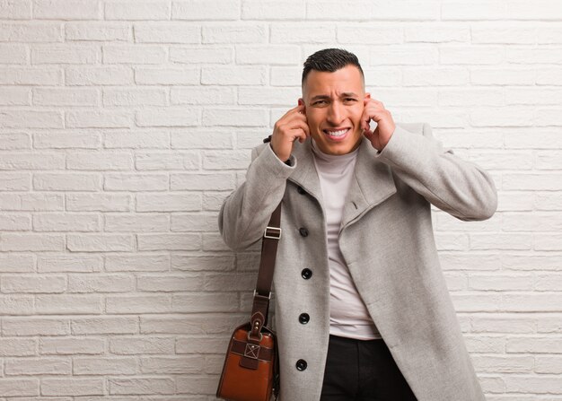 Young latin businessman covering ears with hands