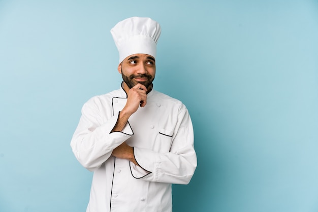 Young latin chef man isolated looking sideways with doubtful and skeptical expression.